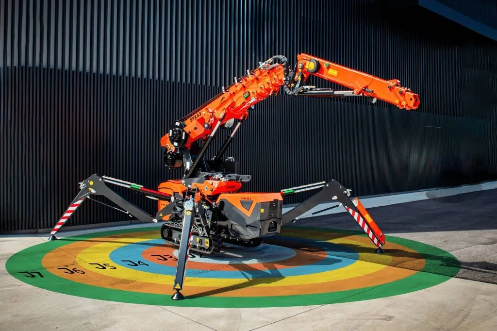 SPX532.2 set up on its four outriggers with the boom raised, in front of a dark industrial building